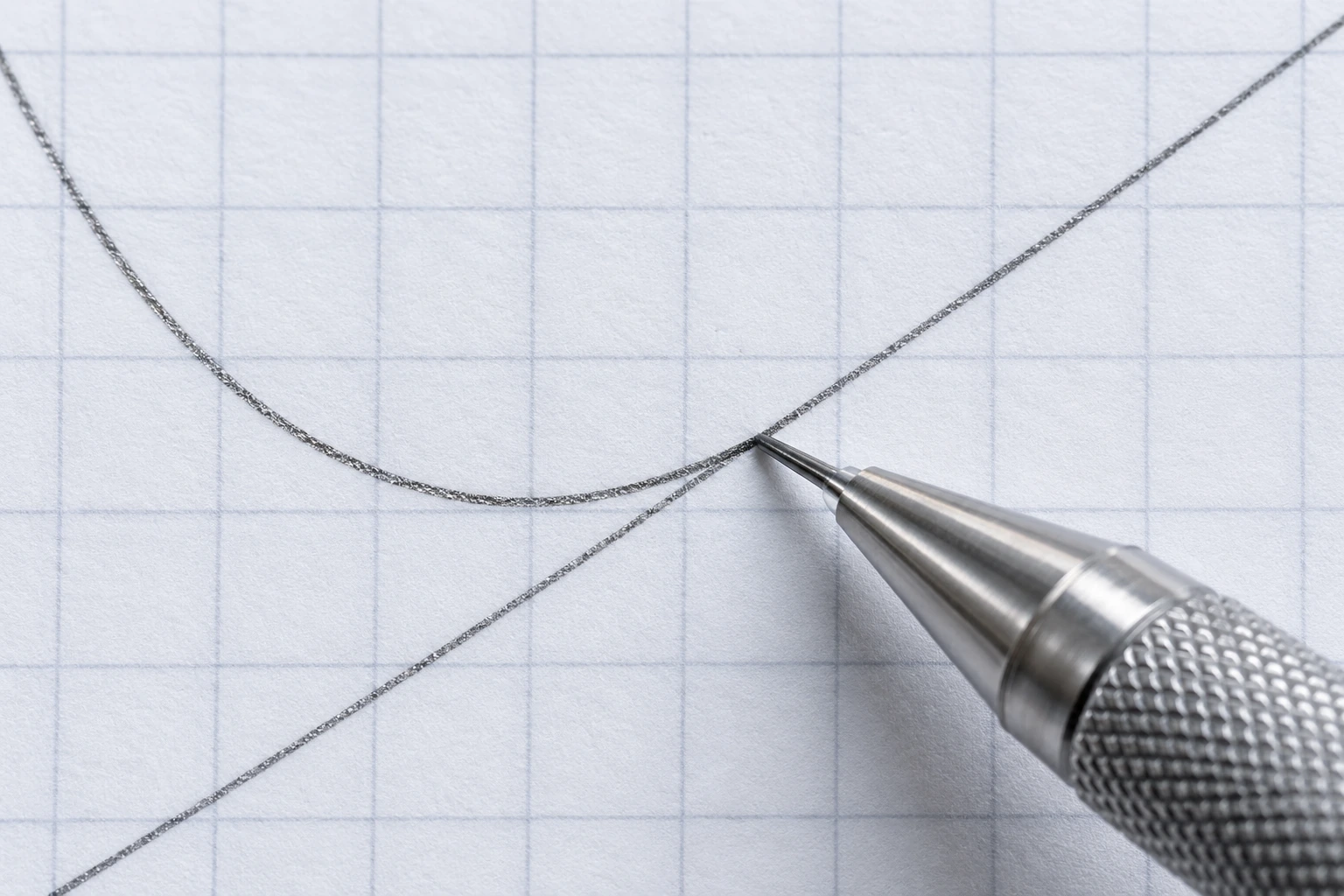 A silver mechanical pencil beside a graphite curve and straight line on squared paper